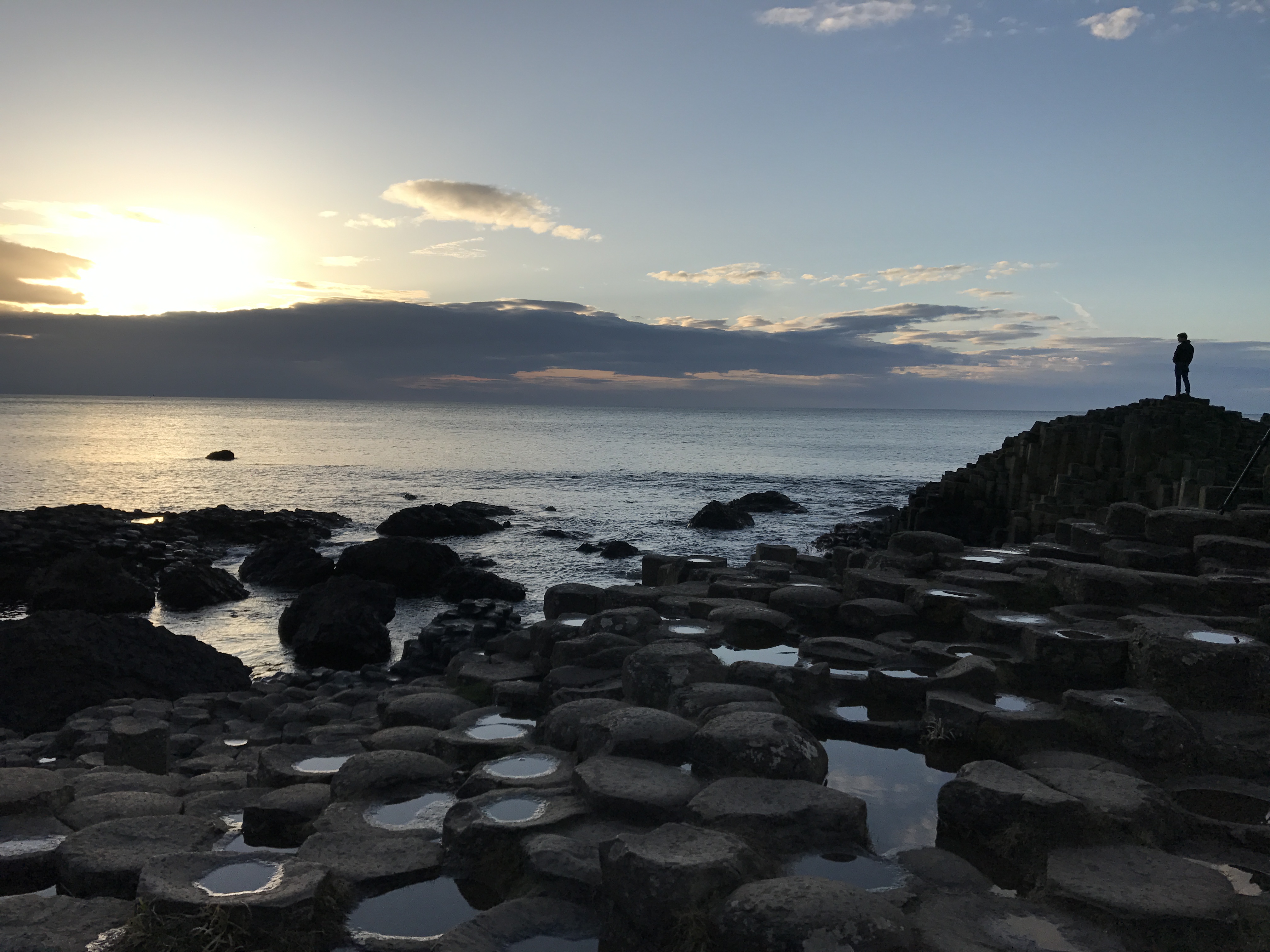 Stones with person looking over calm ocean