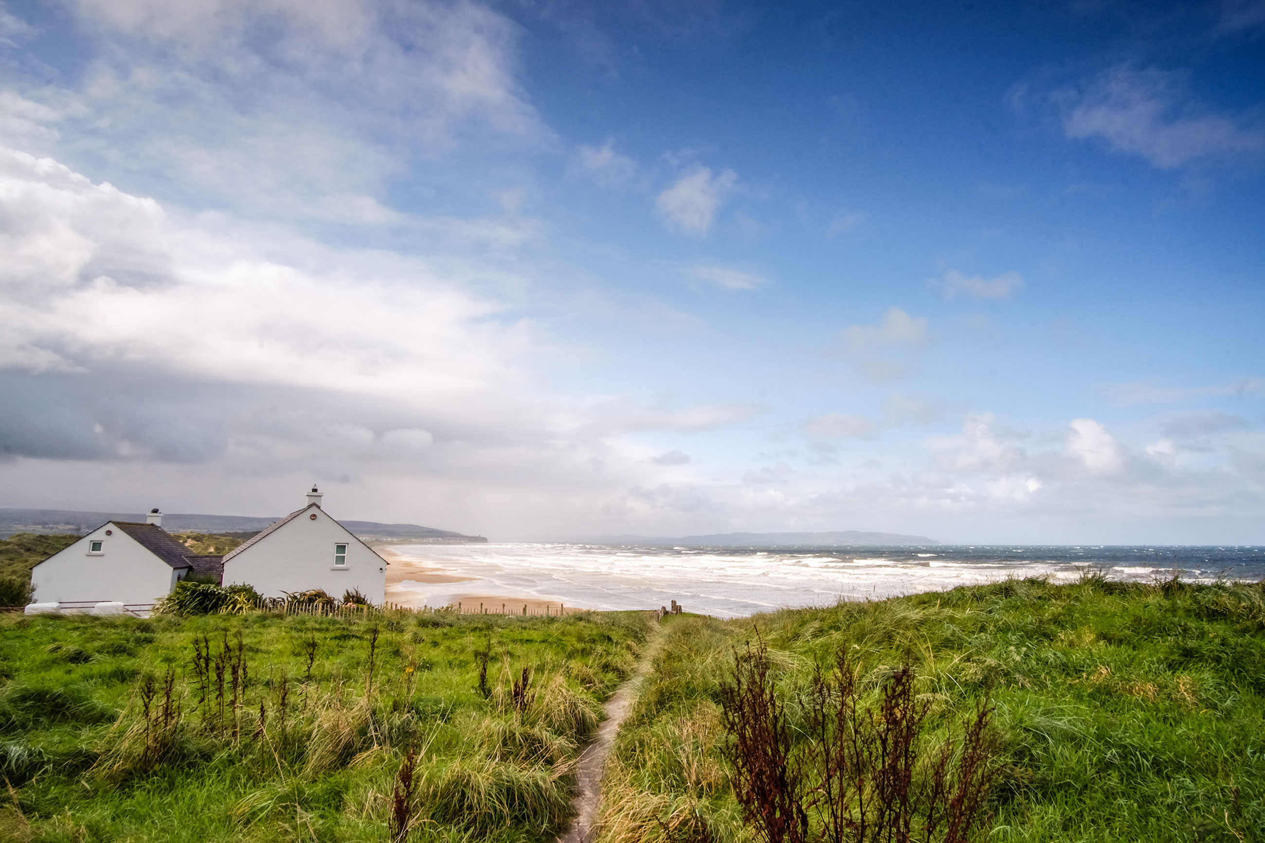 Grassy hill with ocean and white house 